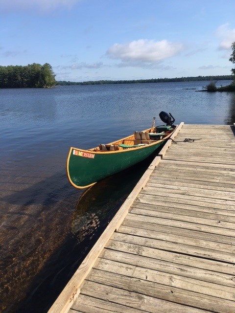 Photo of a green canoe docked on a lake.